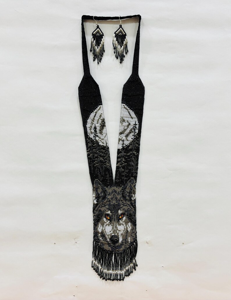 Flat lay of handcrafted wolf seed bead necklace with matching fringe earrings displayed together on a white background.