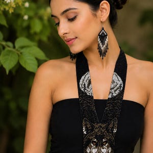 Model wearing a handcrafted wolf seed bead statement necklace and matching fringe earrings inspired by wildlife and forest spirit.