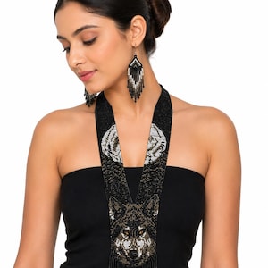 Woman modeling a handcrafted wolf seed bead necklace with coordinating fringe earrings, showcasing artisan beadwork and elegant style.