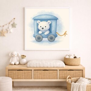May include: Watercolor illustration of a white bear in a blue train car. The artwork is framed in a white square frame. The background is a soft, light blue wash. The train car has two wheels and a yellow rope.