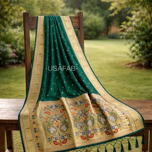 Puede incluir: Textil verde esmeralda con ribete dorado y bordados florales, drapeado sobre una silla de madera. El textil presenta un borde detallado con dise&ntilde;os florales y paisley coloridos. El texto "USAFAB" es visible.