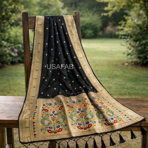 Puede incluir: Un textil negro con ribete dorado y bordado floral colorido est&aacute; drapeado sobre una silla de madera. El textil tiene un patr&oacute;n repetido de peque&ntilde;os puntos dorados y un borde decorativo con borlas. El texto "USAFAB" es visible.