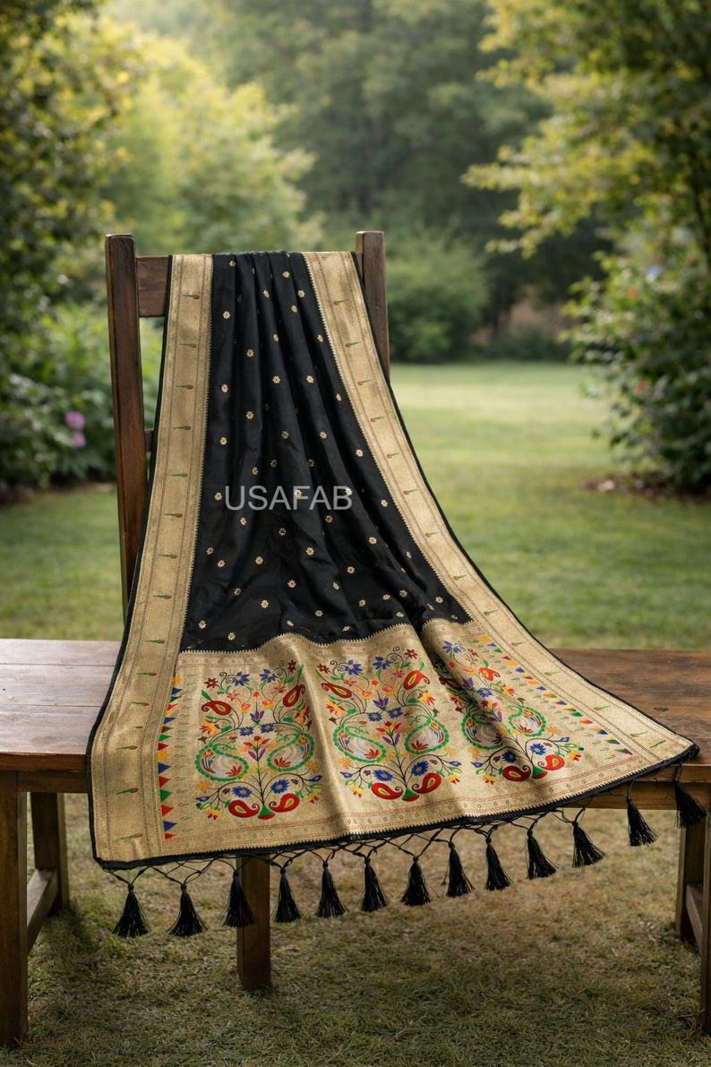 Puede incluir: Un textil negro con ribete dorado y bordado floral colorido est&aacute; drapeado sobre una silla de madera. El textil tiene un patr&oacute;n repetido de peque&ntilde;os puntos dorados y un borde decorativo con borlas. El texto "USAFAB" es visible.