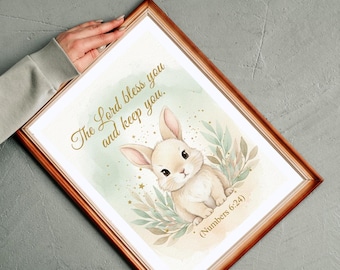 May include: A framed print featuring a watercolor illustration of a bunny surrounded by greenery. The text "The Lord bless you and keep you" is written in elegant script. The frame is a warm brown color.