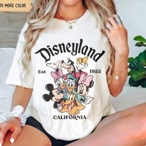 Op de afbeelding: Cr&egrave;mekleurig T-shirt met het Disneyland-logo en diverse stripfiguren. Het shirt bevat de tekst "Disneyland Est 1955 California". Het shirt heeft een relaxte pasvorm.