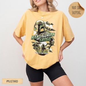 Pu&ograve; includere: T-shirt color senape con grafica di "The Mandalorian and Grogu". Il design include il casco Mandaloriano, Grogu e altri personaggi con la scritta "THIS IS THE WAY". La maglietta ha una vestibilit&agrave; ampia.