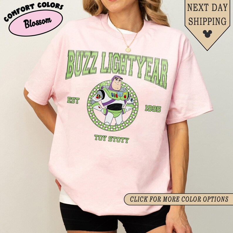 Puede incluir: Camiseta rosa claro con un dise&ntilde;o de Buzz Lightyear. El dise&ntilde;o incluye el texto "BUZZ LIGHTYEAR" en verde, el a&ntilde;o "1995" y las palabras "TOY STOTY". La camiseta tambi&eacute;n tiene el texto "COMFORT COLORS" y "Blossom".