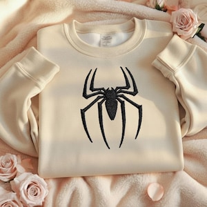 Puede incluir: Sudadera color crema con un dise&ntilde;o de ara&ntilde;a negra bordada en la parte delantera. La ara&ntilde;a est&aacute; detallada. La sudadera tiene cuello redondo y mangas largas con pu&ntilde;os acanalados.