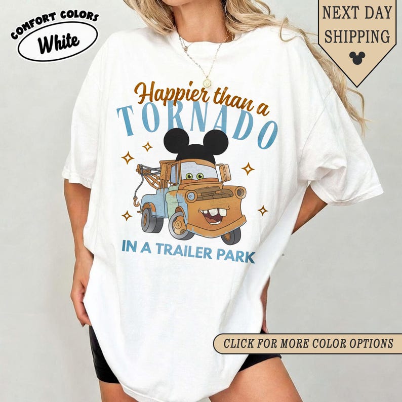 K&ouml;nnte beinhalten: Wei&szlig;es T-Shirt mit einem Zeichentrick-Abschleppwagen mit Mickey Mouse-Ohren, dem Text "Happier than a Tornado in a Trailer Park" und Sternen. Das Shirt hat auch die Worte "Comfort Colors" und "White" in einem Kreis.