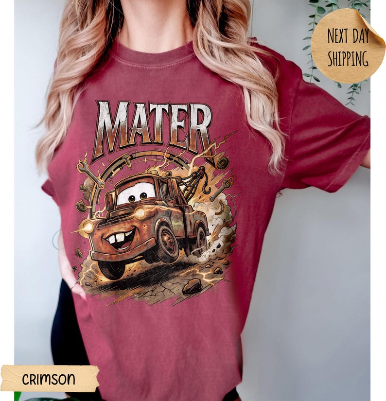May include: Crimson t-shirt with a cartoon image of Mater from the film Cars. The word "MATER" is printed above the image in a distressed font. The graphic includes a tow truck, lightning bolts, and a smiling face, set against a background.
