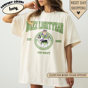 Puede incluir: Camiseta color marfil con la inscripci&oacute;n "BUZZ LIGHTYEAR" en letras verdes sobre un dise&ntilde;o circular de Buzz Lightyear. La camiseta tambi&eacute;n incluye el texto "EST 1995" y "TOY STOTY". La camiseta tiene un corte holgado.