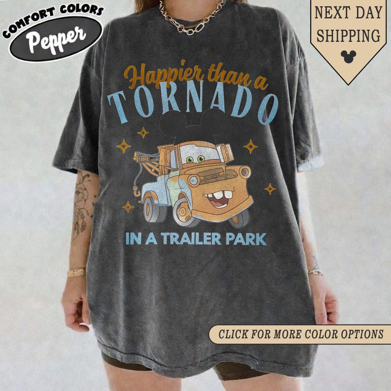 K&ouml;nnte beinhalten: Dunkelgraues T-Shirt mit einem Cartoon-Bild von Hook aus dem Film Cars. Das Shirt tr&auml;gt den Text "Happier than a TORNADO IN A TRAILER PARK" in Blau und Orange. Das Shirt hat auch die Logos Comfort Colors und Pepper.