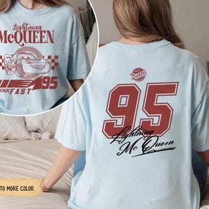 May include: Light blue t-shirt featuring Lightning McQueen graphics. The front displays the text "Lightning McQueen" above a car illustration and the number "95". The back of the shirt has a large "95" and "Lightning McQueen" text.
