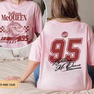 May include: A light pink t-shirt featuring Lightning McQueen graphics. The front displays the character's name, image, and the number 95. The back of the shirt has a large number 95 and the words "Lightning McQueen".