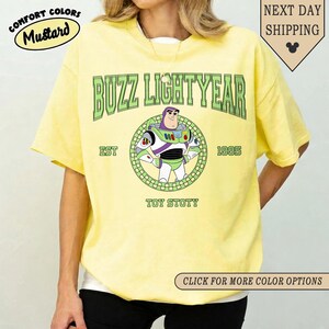 Puede incluir: Camiseta amarilla mostaza con un dise&ntilde;o de Buzz Lightyear de Toy Story. El dise&ntilde;o incluye el texto "BUZZ LIGHTYEAR", "EST 1995" y "TOY STOTY". La camiseta tiene cuello redondo y mangas cortas.
