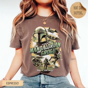Pu&ograve; includere: T-shirt color espresso con grafica di The Mandalorian e Grogu di Star Wars. Il design include l'elmo del Mandaloriano, Grogu e la scritta "THIS IS THE WAY". La maglietta &egrave; girocollo.