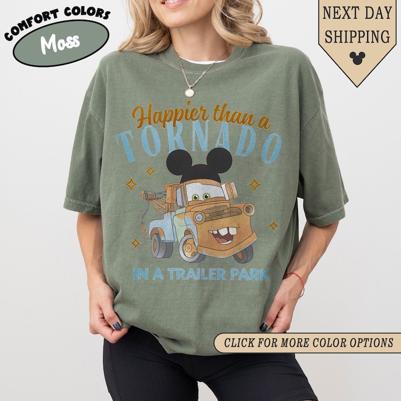 K&ouml;nnte beinhalten: Olivgr&uuml;nes T-Shirt mit dem Text "Happier than a Tornado in a Trailer Park" und einem Cartoon-Bild von Hook aus dem Disney-Film Cars. Das Shirt hat auch den Text "Comfort Colors" und "Next Day Shipping".