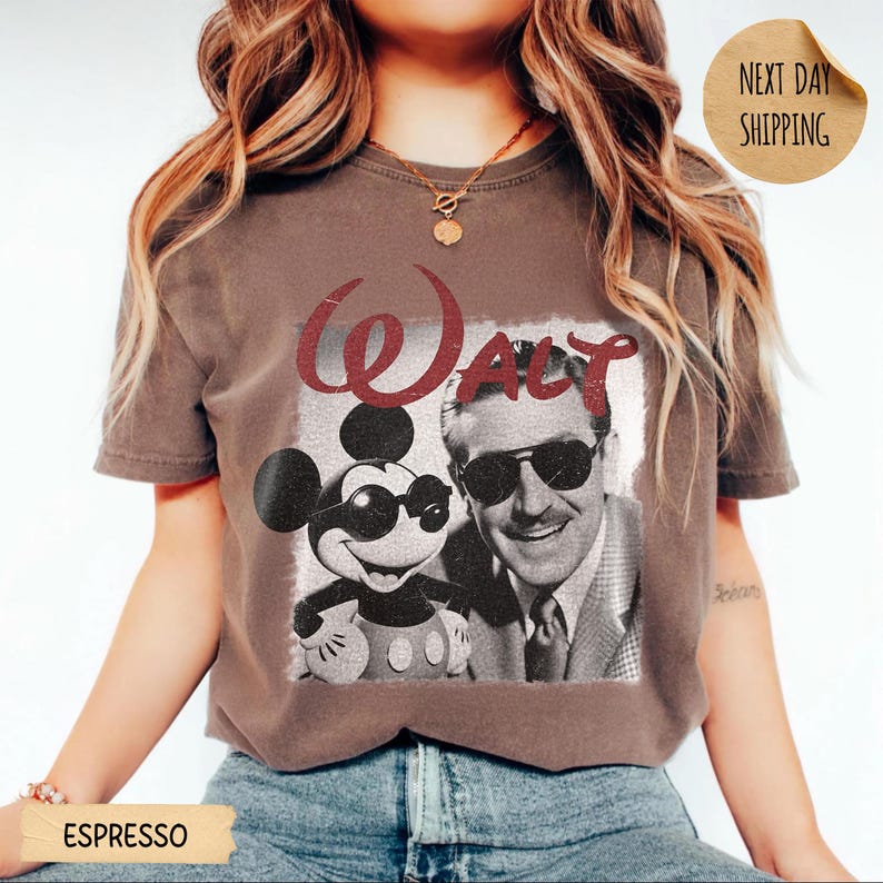 May include: Espresso-colored t-shirt featuring a graphic of Mickey Mouse and Walt Disney, with the word "Walt" in red script. Mickey is wearing sunglasses. The image is in a vintage style.