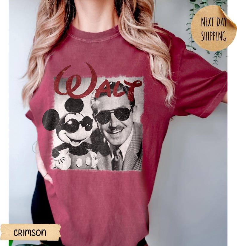 May include: Crimson-colored t-shirt featuring a vintage graphic of Mickey Mouse and Walt Disney wearing sunglasses. The word "Walt" is printed above the image in a stylized font. The shirt has a classic crew neck and short sleeves.