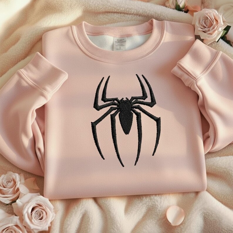 Puede incluir: Sudadera rosa claro con un dise&ntilde;o de ara&ntilde;a negra. La sudadera de cuello redondo tiene mangas largas y pu&ntilde;os y dobladillo acanalados. El dise&ntilde;o de la ara&ntilde;a est&aacute; centrado en la parte delantera.
