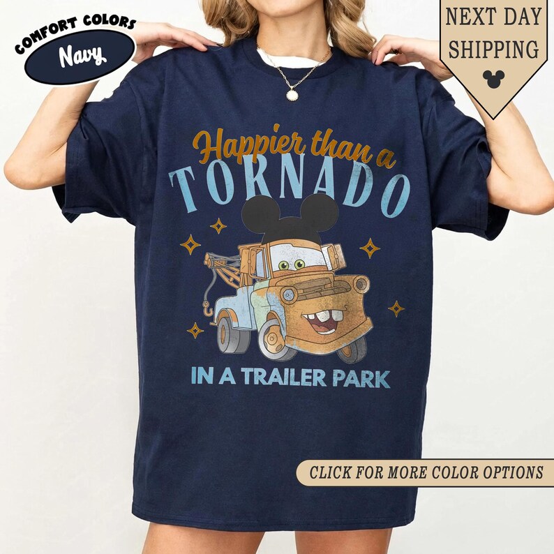 K&ouml;nnte beinhalten: Marineblaues T-Shirt mit einem Cartoon von Hook aus dem Film Cars, mit Mickey Mouse Ohren. Der Text lautet "Happier than a TORNADO IN A TRAILER PARK." Zus&auml;tzlicher Text beinhaltet "COMFORT COLORS Navy" und "CLICK FOR MORE COLOR OPTIONS."
