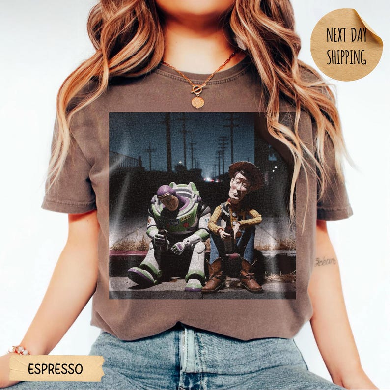 Pode incluir: Camiseta cor caf&eacute; com estampa desgastada de Buzz Lightyear e Woody de Toy Story. Os personagens s&atilde;o retratados sentados em uma cal&ccedil;ada &agrave; noite. A camiseta tem um visual vintage e desgastado.