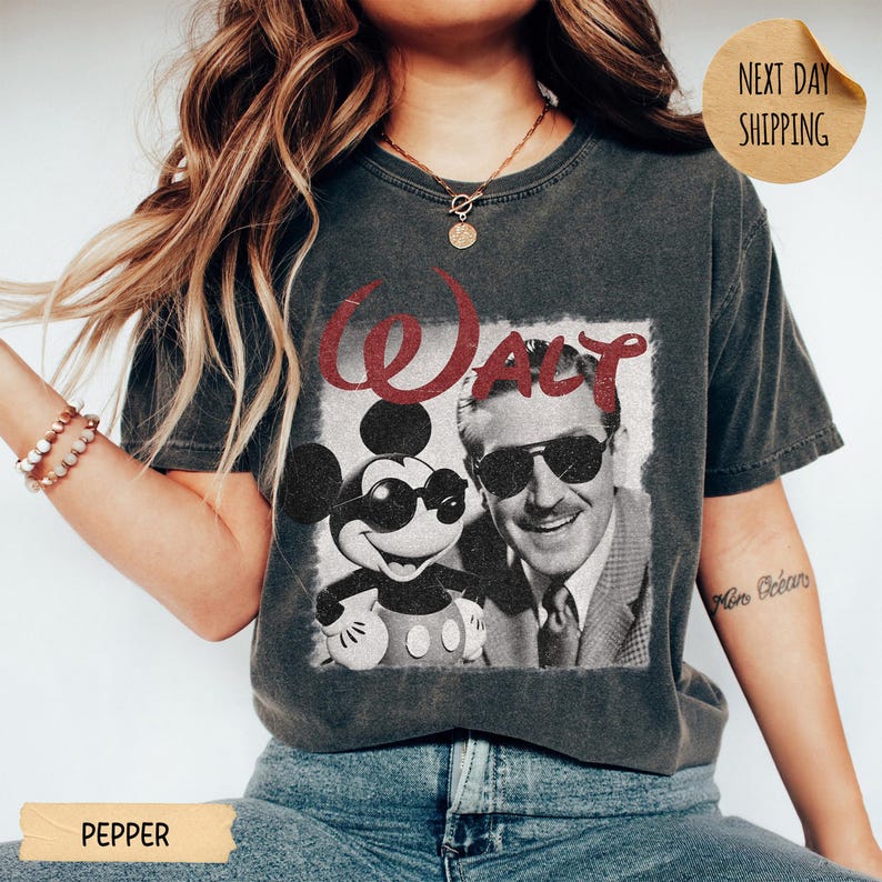 May include: Dark gray t-shirt featuring a vintage graphic of Mickey Mouse and Walt Disney wearing sunglasses. The word "WALT" is printed in red above the image. The shirt is a Pepper color.