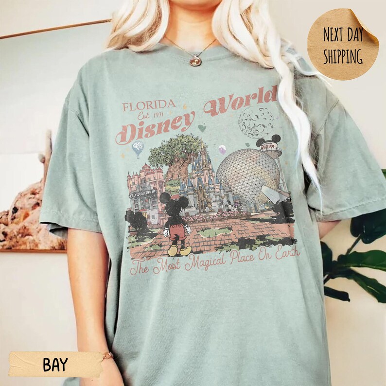 May include: A light green t-shirt featuring a Disney World graphic. The graphic includes Mickey Mouse, a castle, and the text "Florida Disney World" and "The Most Magical Place On Earth."