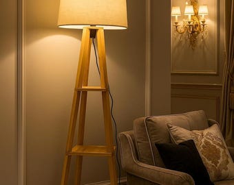 Lámpara de pie moderna de madera con trípode, madera natural, pantalla de tela beige y estante de almacenamiento.