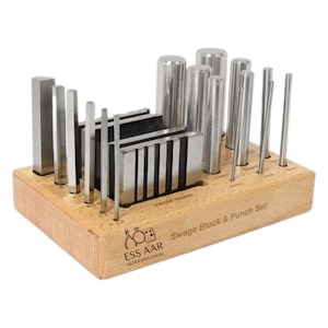 Könnte beinhalten: Ein Swage-Block- und Stanz-Set mit verschiedenen Metallwerkzeugen. Das Set enthält rechteckige und zylindrische Stempel und einen Swage-Block, alles in einer Holzbasis. Der Text "Swage Block & Punch Set" ist sichtbar.