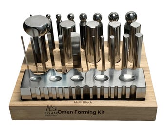 Può includere: Un kit per la formatura di gioielli in metallo con strumenti metallici di varie forme e dimensioni. Gli strumenti sono disposti su una base di legno con il testo "Multi Block" e "Omen Forming Kit". Il kit include strumenti cilindrici, sferici e a estremità piatta.