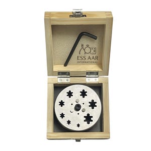 Pode incluir: Uma caixa de madeira clara contendo um disco metálico circular com vários recortes em forma de peças de puzzle e uma pequena chave hexagonal preta. A tampa interior apresenta o texto ESS AAR INTERNATIONAL e ícones de ferramentas.