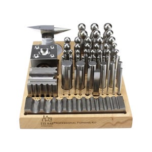 Könnte beinhalten: Ein professionelles Formwerkzeug-Set mit verschiedenen Metallbearbeitungswerkzeugen. Das Set enthält einen Amboss, Formblöcke und eine Vielzahl von Stahlstempeln und -einsätzen. Die Werkzeuge sind in einer Holzbasis angeordnet. Der Text lautet "ESS AAR PROFESSIONAL FORMING KIT INTERNATIONAL".
