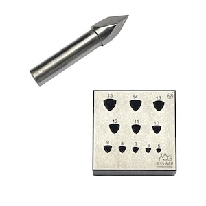 May include: A stainless steel bezel block with shield-shaped cutouts numbered 5 to 15 and 17. A silver metal punch tool with a pointed tip is also shown. The text "ESS AAR INTERNATIONAL" is visible.