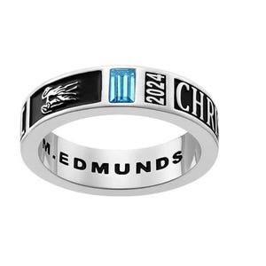 May include: A silver ring with a rectangular light blue gemstone. The ring features black enamel sections with a dragon and the year "2024". The word "CHRIST" is visible on the ring's side, and "M.EDMUNDS" is engraved inside.