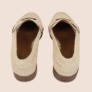 Puede incluir: Vista a&eacute;rea de dos mocasines beige tejidos con suelas y detalles marrones. Los zapatos tienen un dise&ntilde;o cl&aacute;sico sin cordones, punteras redondeadas y una correa decorativa. El interior es de color marr&oacute;n contrastante.