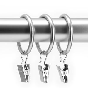 May include: Three silver curtain rings with clip hooks. The rings are attached to a silver curtain rod.