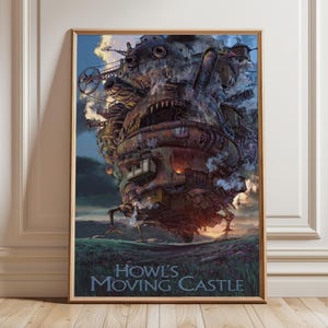 Op de afbeelding: Een ingelijste poster met de animatiefilm "Howl's Moving Castle". De afbeelding toont het kasteel met zijn mechanische details, tegen een achtergrond van een zonsonderganghemel en een grasveld. De titel staat onderaan.