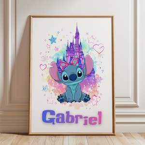 Op de afbeelding: Ingelijste kunstdruk met een stripfiguur met grote oren en een strik, tegen een kasteel. Het personage is blauw met een roze strik. De naam "Gabriel" staat in kleurrijke letters onderaan.