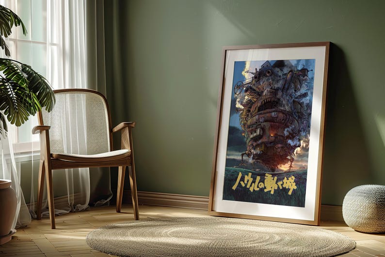 May include: Framed art print featuring a detailed illustration of a fantastical, moving castle with a fiery glow. The artwork has a brown wooden frame and is leaning against a green wall. Japanese text is visible at the bottom of the print.