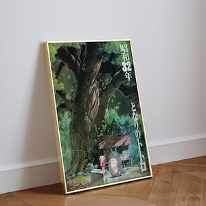 Pu&ograve; includere: Poster incorniciato con una scena del film d'animazione Il mio vicino Totoro. L'opera raffigura un grande albero, una bambina e Totoro, con testo giapponese. Il poster &egrave; in una cornice dorata e appoggiato a un muro.