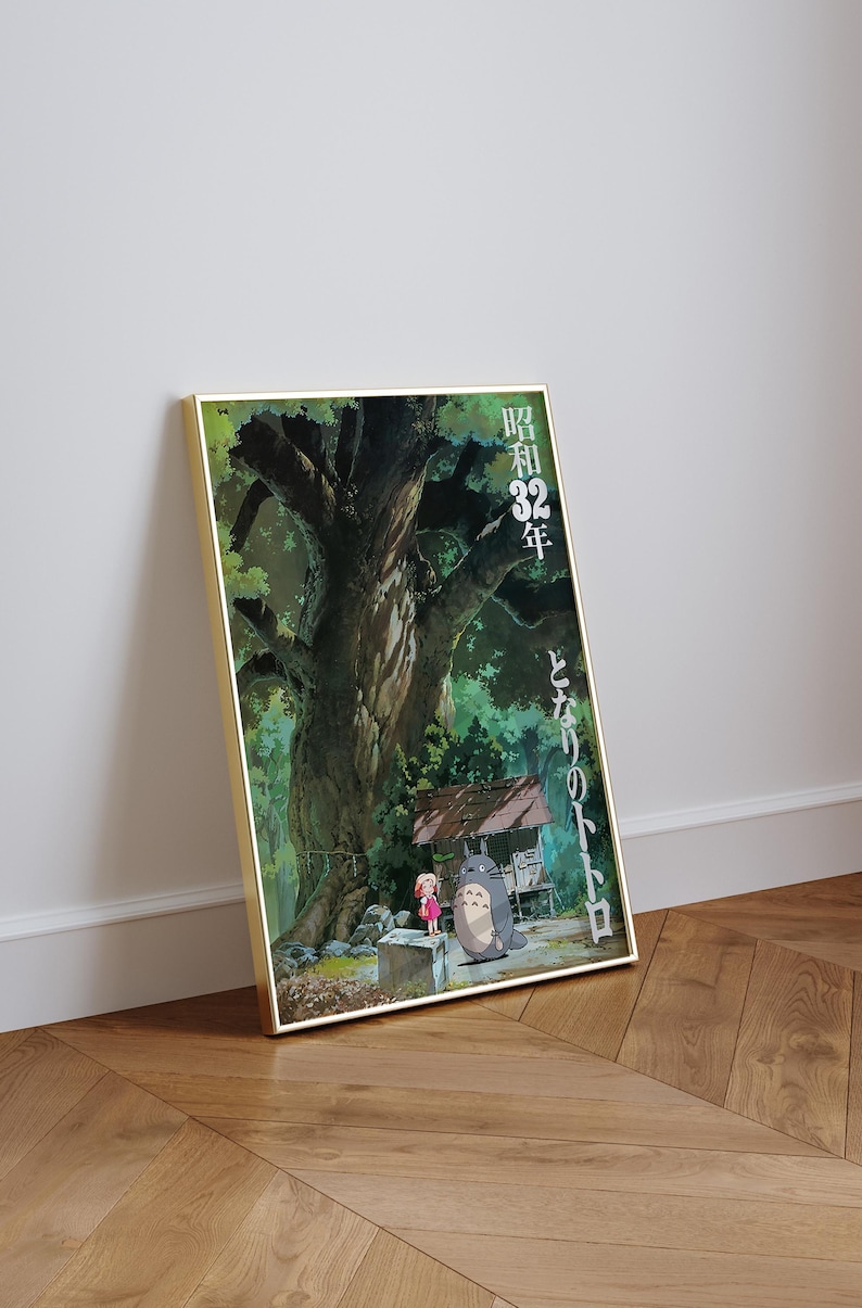 Pu&ograve; includere: Poster incorniciato con una scena del film d'animazione Il mio vicino Totoro. L'opera raffigura un grande albero, una bambina e Totoro, con testo giapponese. Il poster &egrave; in una cornice dorata e appoggiato a un muro.
