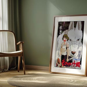 May include: Framed poster featuring a Japanese anime illustration. The artwork depicts a young woman with a wolf-like creature, with Japanese text. The poster is in a wooden frame, leaning against a green wall.