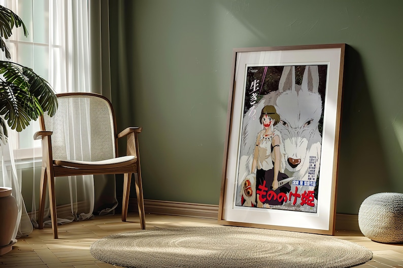 May include: Framed poster featuring a Japanese anime illustration. The artwork depicts a young woman with a wolf-like creature, with Japanese text. The poster is in a wooden frame, leaning against a green wall.