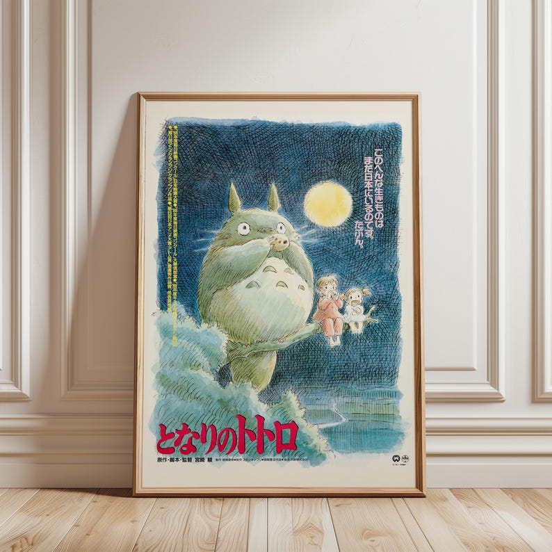 Puede incluir: P&oacute;ster enmarcado con el personaje de animaci&oacute;n Totoro de la pel&iacute;cula "Mi vecino Totoro". La obra de arte representa a Totoro bajo una luna llena con dos ni&ntilde;os. Texto japon&eacute;s visible en rojo y blanco.