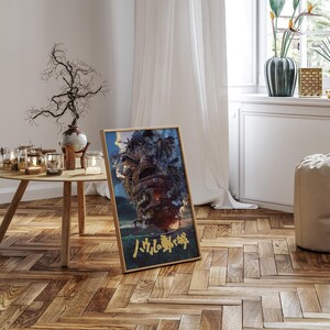 May include: A framed poster featuring a detailed illustration of a moving castle with smoke billowing from its top. The artwork is set against a blue sky and green landscape. Japanese text is visible at the bottom of the poster. The poster is displayed on a wooden floor.