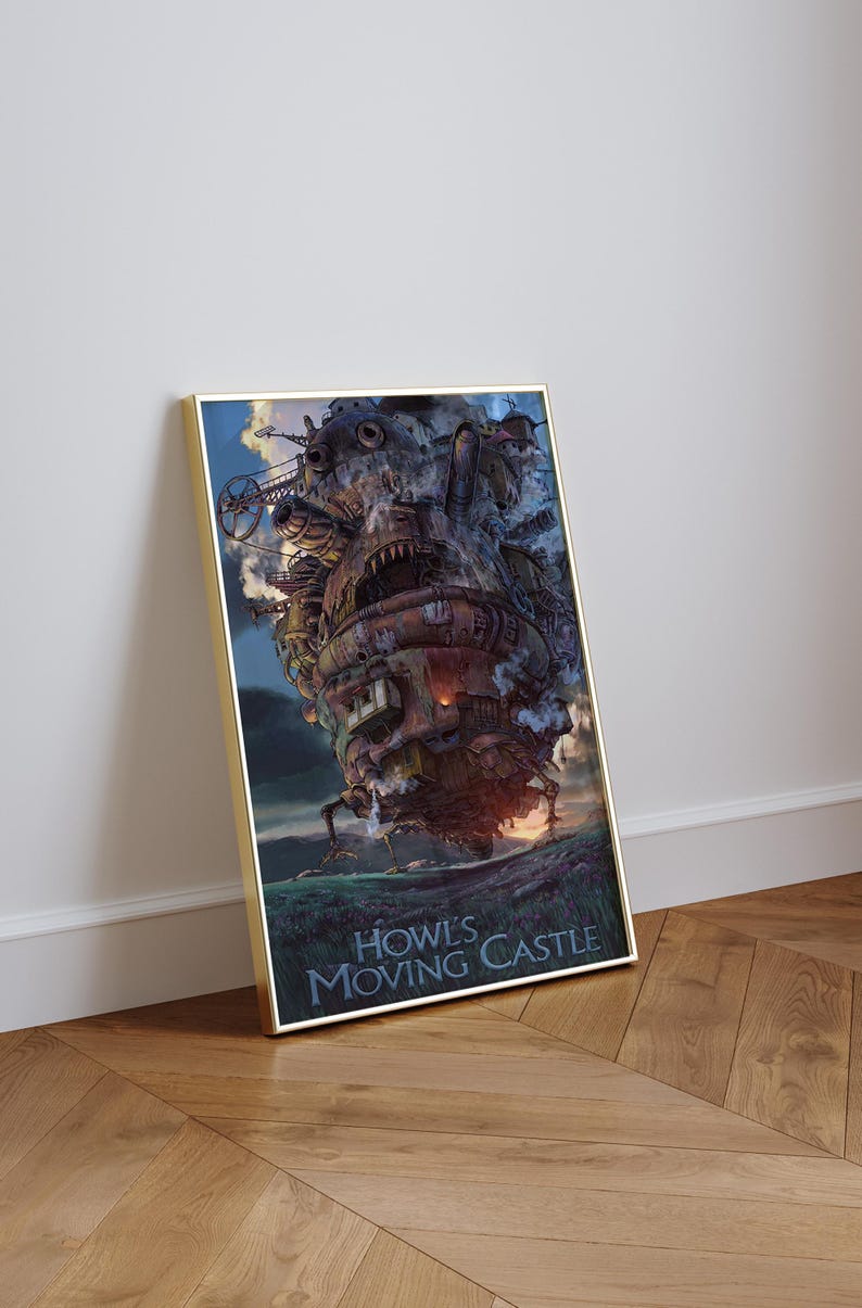 Op de afbeelding: Een ingelijste print van Howl's Moving Castle. Het kunstwerk toont het kasteel met ingewikkelde details, tegen een bewolkte lucht en een grasachtig terrein. De titel staat onderaan.