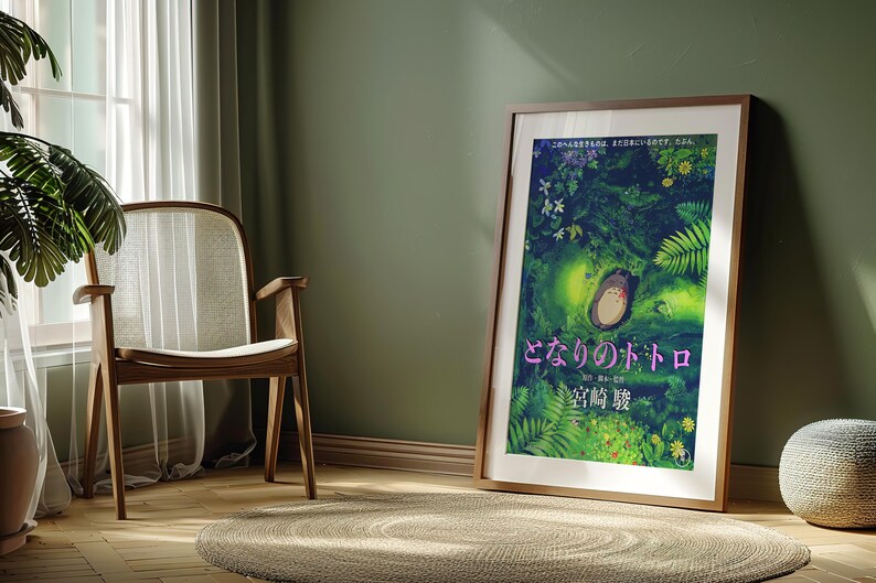 Peut inclure: A framed poster of the animated film "Mon Voisin Totoro." The illustration shows Totoro in a green forest, with Japanese text. The poster is displayed in a room with a wooden chair and a round rug, creating a warm atmosphere.