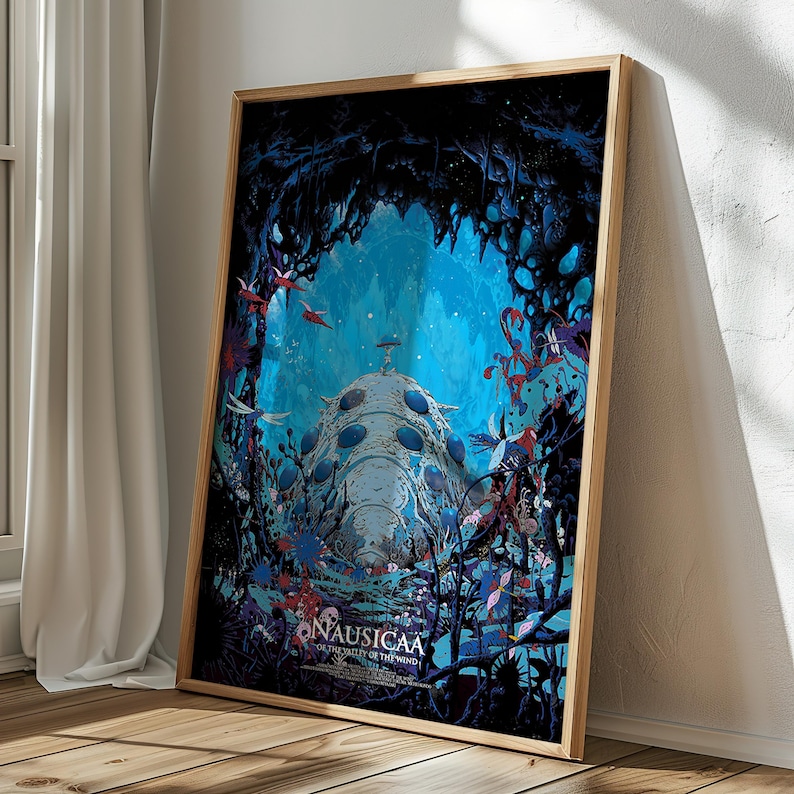 May include: Framed art print of a fantasy scene with a large, light blue, dome-shaped structure in a blue cave. The print features the text "Nausicaa of the Valley of the Wind" in white. The artwork is framed in a light brown wooden frame.