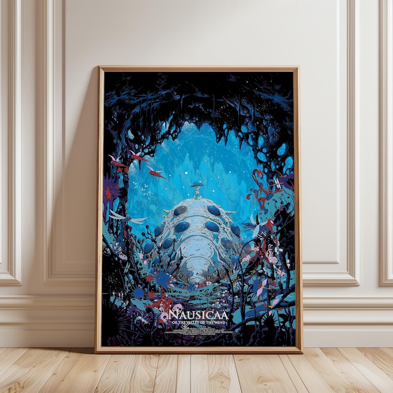 May include: Framed art print featuring a fantastical scene with a large, light blue structure at the center, surrounded by vibrant flora and fauna. The artwork has a dark blue and turquoise color palette, with the text "Nausicaa of the Valley of the Wind" at the bottom.